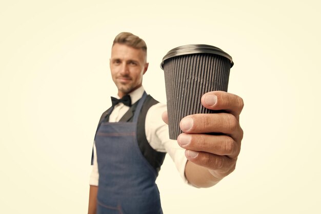 Хорошего дня Возьмите свой кофе Бариста в фартуке подает кофе Концепция кофейни Зрелый бариста держит напиток Попробуйте кофеиновый напиток Энергетическая подзарядка Бородатый мужчина-бармен держит бумажную чашку кофе