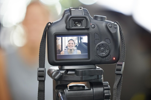 Photo have a vision shot of a young woman using a camera to record for her vlog in a gym