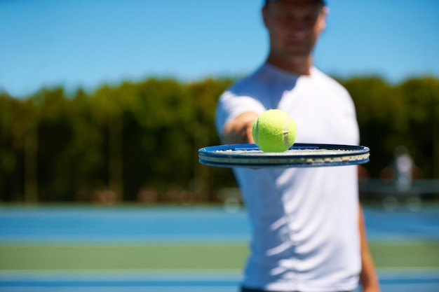 Hai quello che serve inquadratura di un uomo che tiene in equilibrio una pallina da tennis sulla sua racchetta