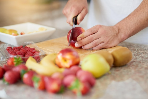 Сделайте себе кадр из фруктового дня, на котором молодой человек готовит фруктовый салат на своей кухне.