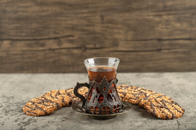 Haverchocoladekoekjes met glas zwarte thee op steen.