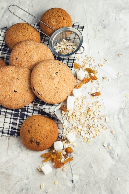 Havermout koekjes op linnen servet en stenen oppervlak. Havermout, rozijnen, suikerklontjes. Scène uit het ontbijt