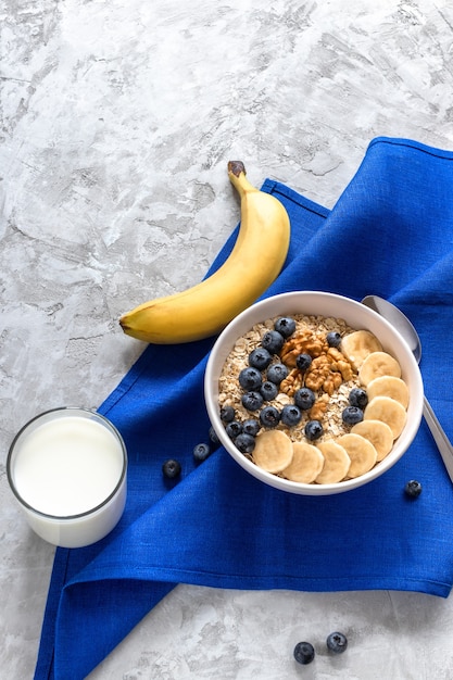 Foto havermout met bananen, bosbessen en walnoot en glas melk voor een gezond ontbijt