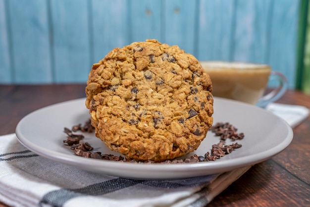 havermoutkoekje en chocochip vergezeld van een kopje koffie met melk.