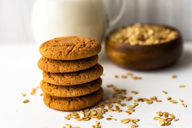 Havermoutkoekjes en havergranenvlokkenkom op witte tafel op melkglazen kruikachtergrond