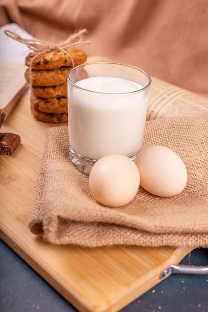 Havermoutkoekjes met chocoladeschilfers, eieren en een glas melk op een stuk jute