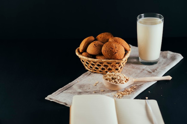 Havermoutkoekjes met een glas melk op een servet op een zwarte achtergrond Het concept van een gezond ontbijt