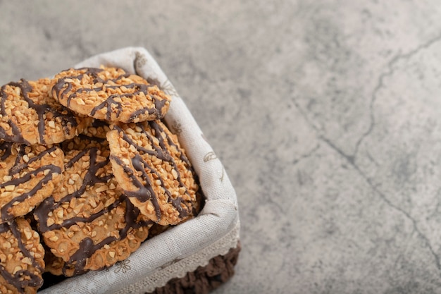 Havermoutkoekjes versierd met geglazuurde chocolade in een rieten mand.