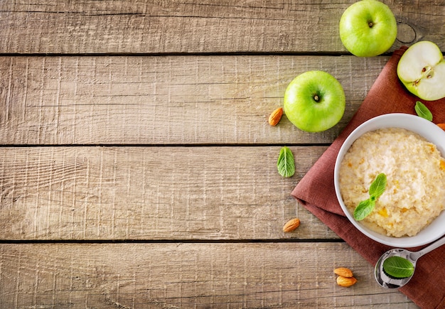 Havermoutkom met muntblaadjes en appels op houten ondergrond. Bovenaanzicht. Ruimte kopiëren.