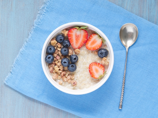 Havermoutpap met verse aardbeien, bosbessen, muesli op blauwe achtergrond.