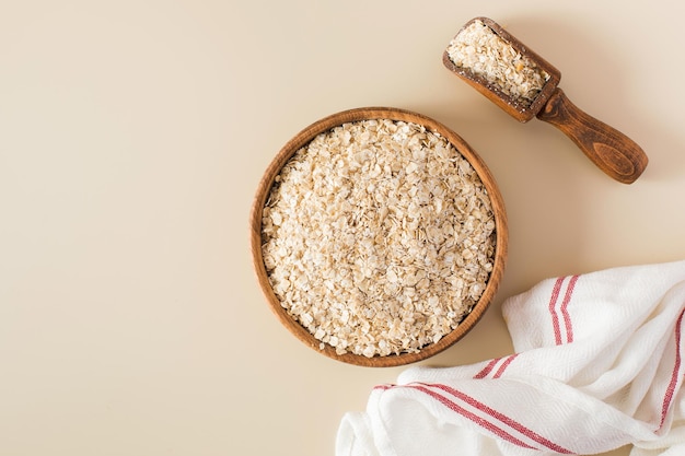 Havervlokken in een houten kom op een beige achtergrond Gezond eten