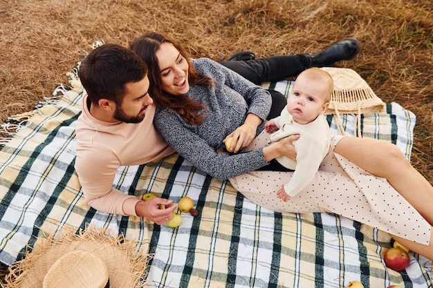 ピクニックをしている母家族の幸せな家族と小さな赤ちゃんは屋外で休んでいます美しい晴れた秋の自然