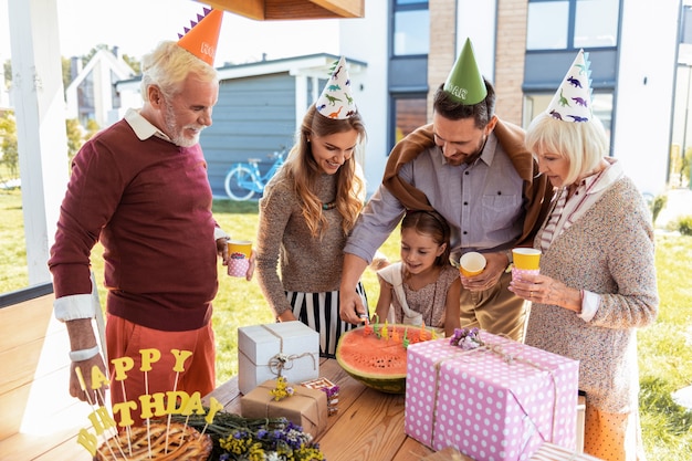 Having birthday. attentive blonde woman holding paper cup in left hand while looking at watermelon