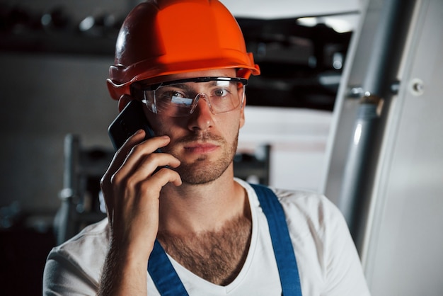 Avere conversazione. ritratto di ingegnere in fabbrica metallurgica in casco protettivo e occhiali.