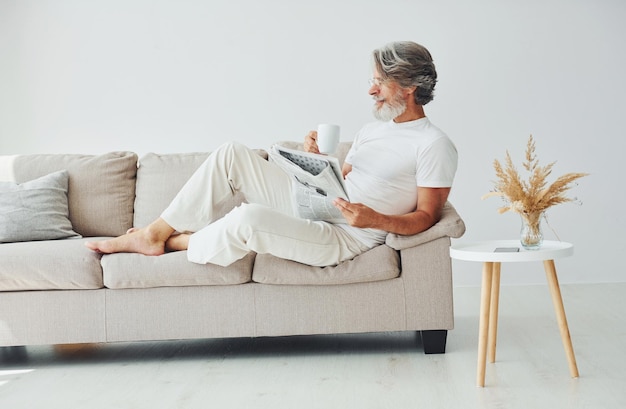 Having free time Senior stylish modern man with grey hair and beard indoors