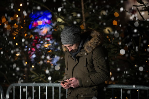 Having Fun at a Christmas Fairy  Young Cheerful Man Dressed Warm Is Standing In Holiday Market