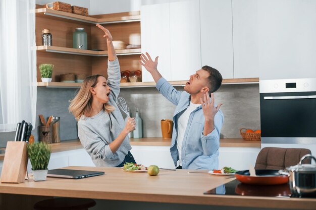 Having fun couple preparing food at home on the modern\
kitchen