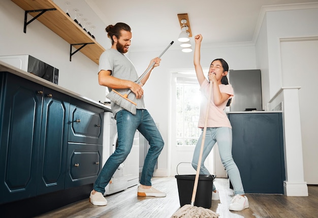 Having fun doing chores dancing and singing father and daughter cleaning the living room together at home Carefree happy and cheerful parent bonding doing housework and playing with little girl