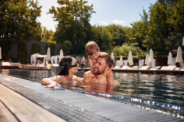 Foto divertirsi famiglia felice di padre madre e figlio sono in piscina