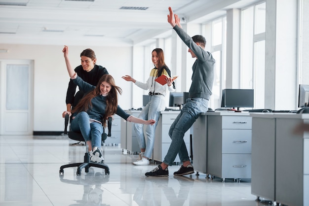 Having fun in the office. Young people have a break and driving by using a seat