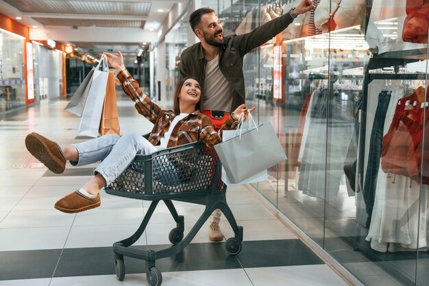 Having fun riding in the cart Young couple are in supermarket together