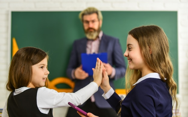 Divertirsi. bambine a scuola. di nuovo a scuola. insegnante e alunni che lavorano insieme alla scrivania della scuola elementare. divulgare e sviluppare la creatività. insegnante che lavora con creative kids.