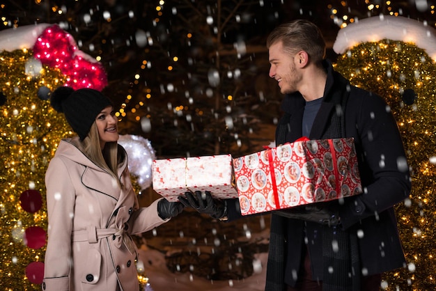 Divertirsi insieme a una fata di natale la giovane coppia allegra sta facendo una passeggiata godendosi vestiti caldi, guardandosi l'un l'altro e ridendo