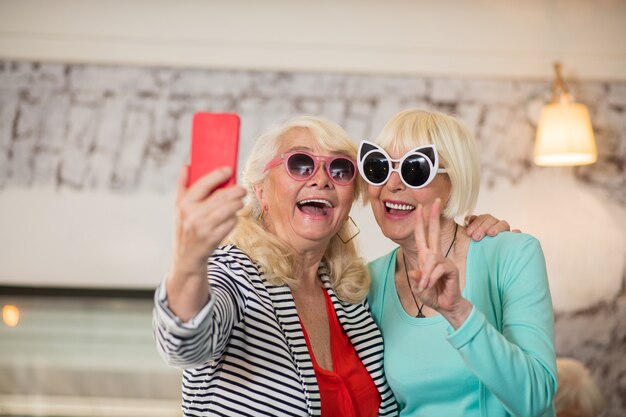 Having fun. Two senior excited women making selfie and having fun