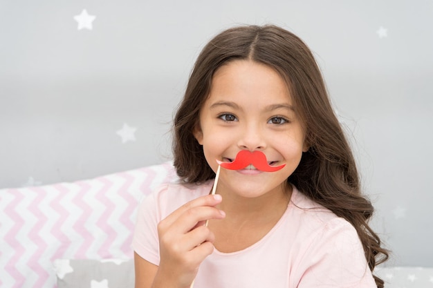 Having fun with face mustache Happy small girl Small girl hold fake mustache on face Happy childhood My childhood is amazing