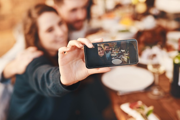 Having a good time with the ones I love Cropped shot of a young woman taking a selfie while at a dinner party