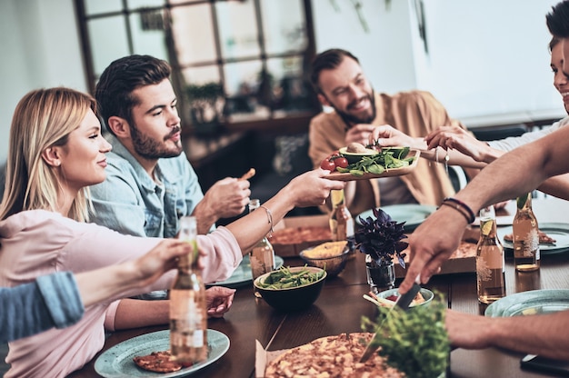 素晴らしい時間を過ごしています。カジュアルな服を食べて笑っている若者のグループ