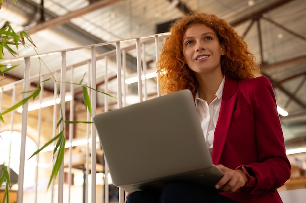 Having inspiration. Businesswoman wearing smart watch having inspiration while working on laptop