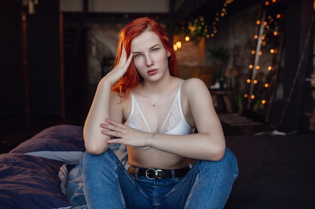 Having a rest. Portrait of a sexy redhead girl on the floor posing in the wooden room.