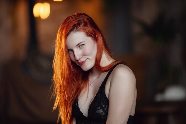 Having a rest. Portrait of a sexy redhead girl on the floor posing in the wooden room.