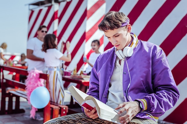 Having rest. Serious brunette man bowing head while reading book