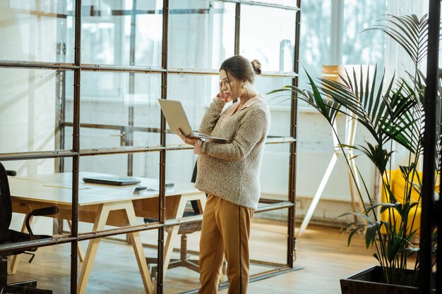 Having video chat. Pregnant businesswoman wearing beige sweater having video chat on laptop