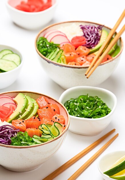 Hawaii salmon poke avocado rice seaweed cucumber radish carrot\
in bowl home made vegetarian poke seafood concept asian salmon poke\
salad on white background