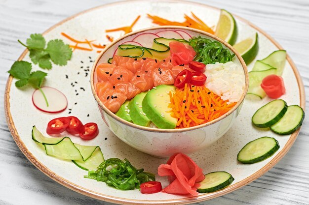 Hawaii salmon poke avocado rice seaweed cucumber radish carrot\
in bowl home made vegetarian poke seafood concept asian salmon poke\
salad on white wood background