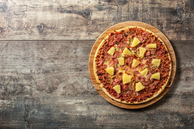 Hawaiiaanse pizza met ananas, ham en kaas op houten tafel