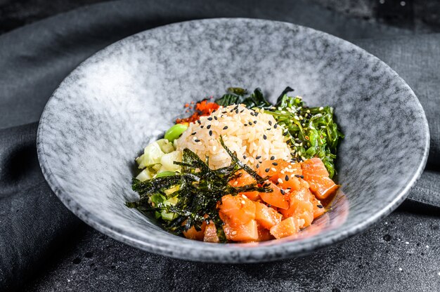 Hawaiiaanse zalm poke kom met zeewier, avocado, sesamzaadjes. zwarte achtergrond. bovenaanzicht