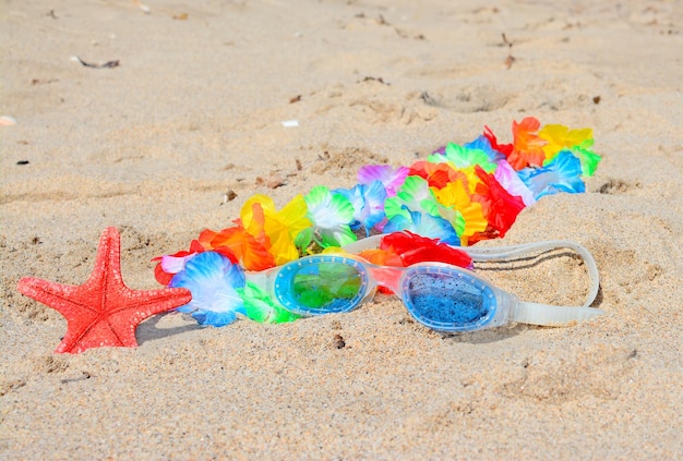 Hawaiian necklace and beach goggles on the sand