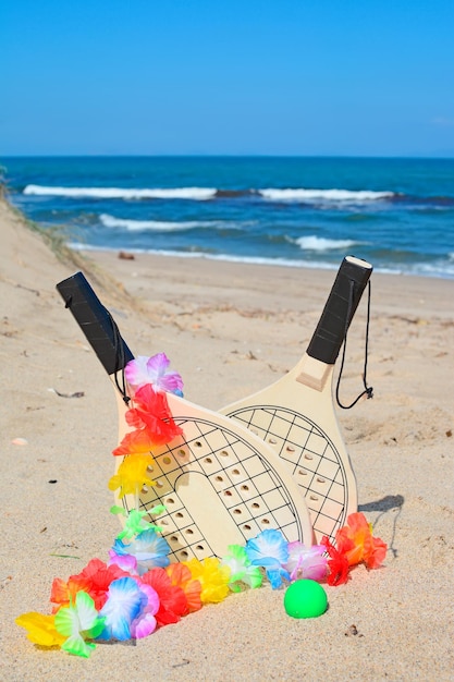 Hawaiian necklace and wooden rackets on the sand