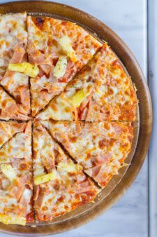 La pizza hawaiana è un alimento italiano fatto con salsa di pomodoro, ananas tritato, prosciutto e formaggio.