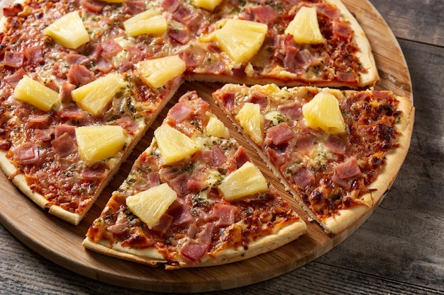 Hawaiian pizza with pineapple,ham and cheese on wooden table