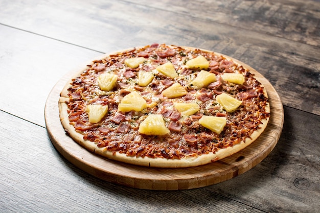 Hawaiian pizza with pineappleham and cheese on wooden table