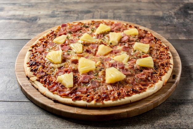 Hawaiian pizza with pineappleham and cheese on wooden table