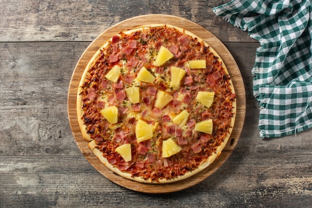 Hawaiian pizza with pineappleham and cheese on wooden table