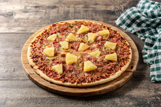 Hawaiian pizza with pineappleham and cheese on wooden table