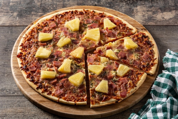 Hawaiian pizza with pineappleham and cheese on wooden table