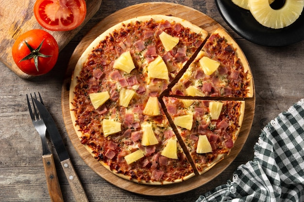 Hawaiian pizza with pineappleham and cheese on wooden table